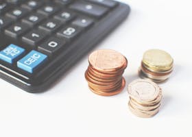 Close-up of stacked coins and a calculator symbolizing financial strategy and budgeting.