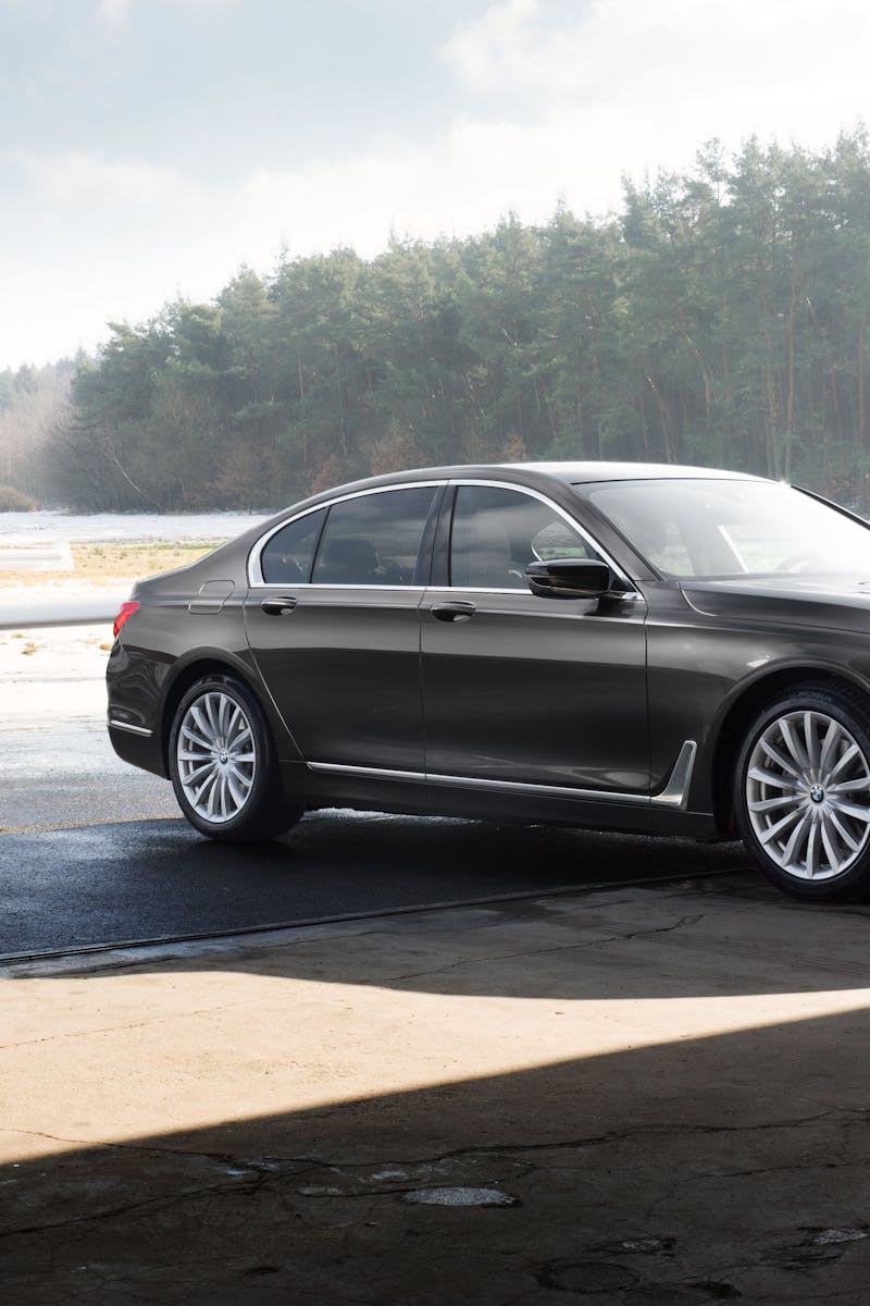 A luxury car parked in front of a small airplane at a sunlit airfield.