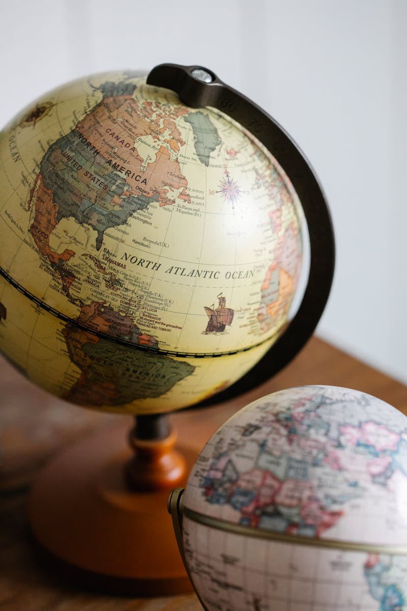 Aesthetic photo of vintage world globes placed on a wooden table indoors.